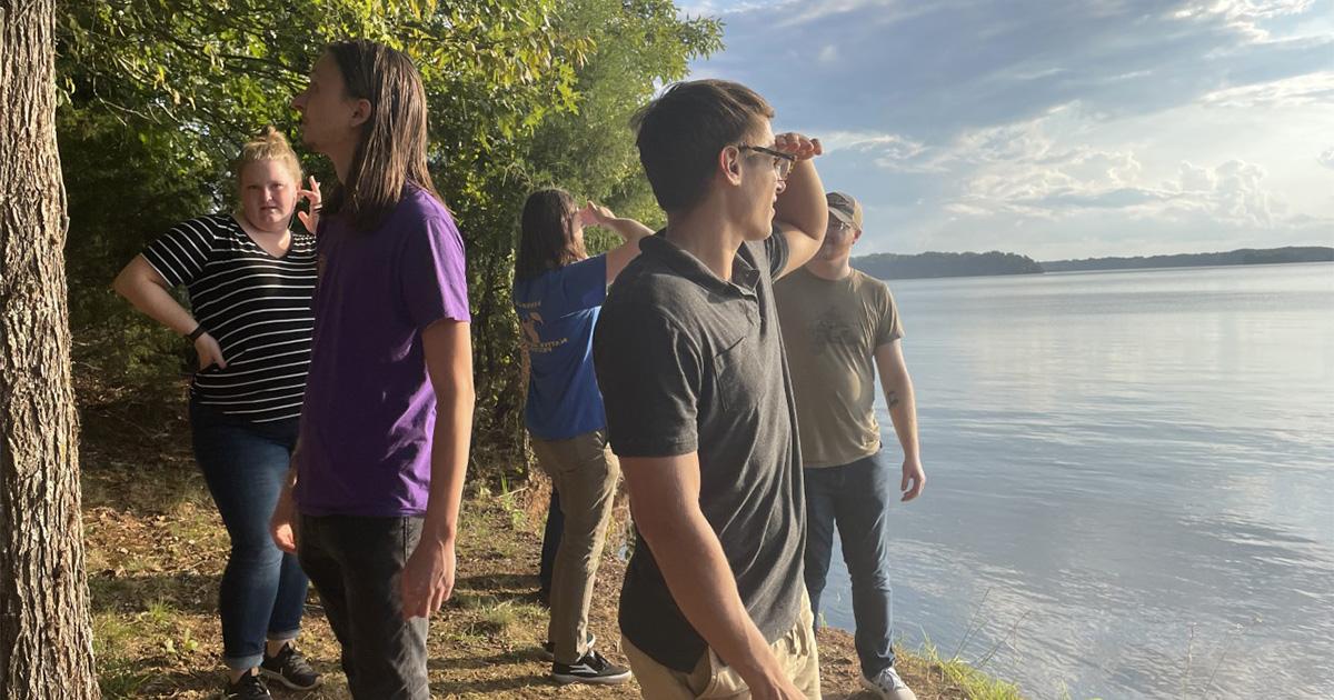 Students stand on the edge of the Tennessee River.